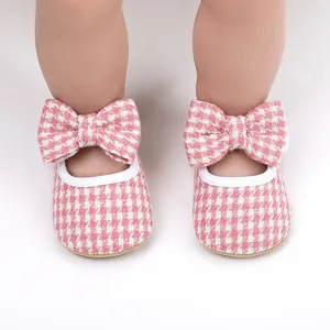 Detailed view of pink houndstooth baby girl pre-walker shoes with large bow decoration