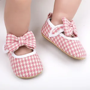 Close-up of pink houndstooth baby girl walking shoes with decorative bow detail