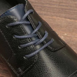 Macro detail of premium men's pebbled grain leather business shoe with blue woven laces