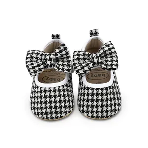 Detailed view of baby walker shoes with black and white houndstooth pattern and bow.