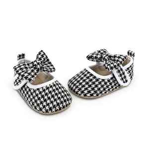 Close-up of stylish baby girl walking shoes featuring a classic houndstooth pattern and bow