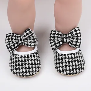 Detailed macro shot of stylish houndstooth baby pre-walker shoes with a large bow decoration