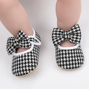 Close-up of baby walking shoes with houndstooth pattern and large bow detail