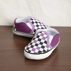 Scarpe da neonato a scacchi viola con suole bianche morbide antiscivolo su legno
