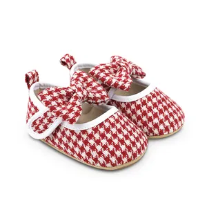 Detailed close-up of infant baby girl pre-walker shoes with red houndstooth pattern and bow