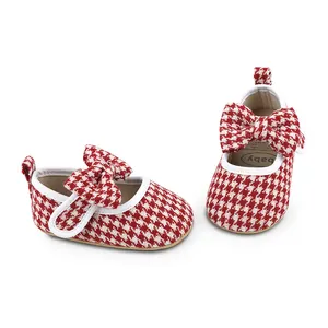 Close-up detail of red and white houndstooth baby walking shoes with large bow decoration