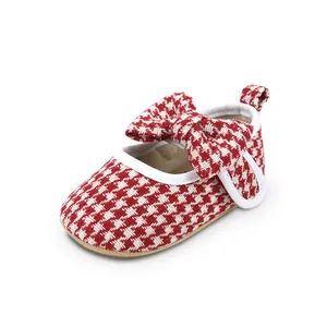Close-up of red and white houndstooth baby girl walking shoe with large bow detail