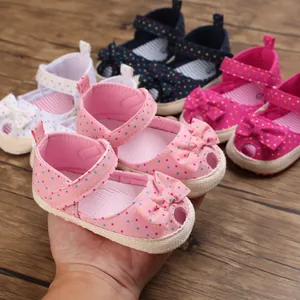 Detailopname van zachte baby-loopzool sandalen met vrolijke stippen en een decoratieve strik