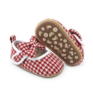 Detail of red houndstooth baby walking shoes with bow and anti-slip sole for girls.