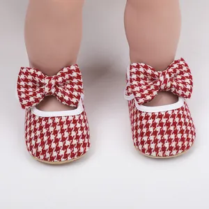 Close-up of red and white houndstooth baby girl walking shoes with decorative bows