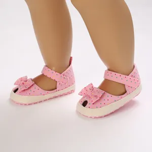 Detail van roze baby sandalen met stippen, strik en klittenbandsluiting
