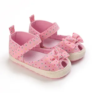 Gedetailleerd overzicht van roze baby sandalen met stippen, zachte zolen en strikken