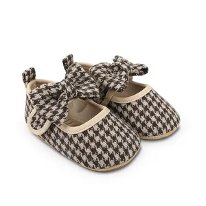 Detail view of brown and cream houndstooth baby girl walking shoes with a decorative bow