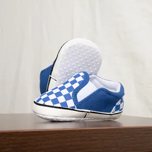 Dettaglio ravvicinato delle scarpe da passeggio per neonati a scacchi blu con suole morbide