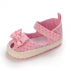 Gedetailleerde weergave van roze baby sandalen met stippen, strik en zachte zool