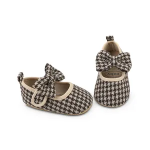 Houndstooth baby pre-walker shoes with a decorative bow on a white background.