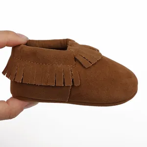 Detailaufnahme von weichem braunem Wildleder-Babyschuh mit dekorativem Fransenbesatz.