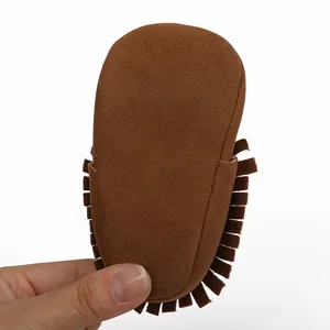 Detailaufnahme eines braunen Wildleder-Babyschuhs mit weicher Sohle und modischen Seitenfransen