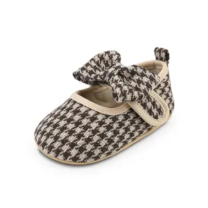 Detailed view of a baby girl walking shoe featuring brown houndstooth pattern and bow