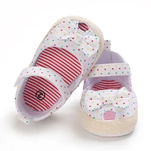 Detailopname van witte baby-loopschoentjes met kleurrijke stippen en strikjes.