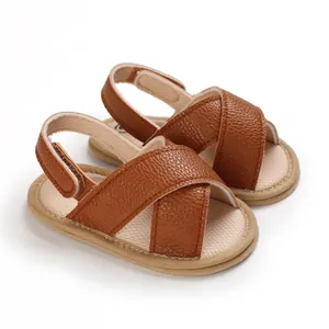 Detalle de sandalias de bebé en cuero sintético marrón con suelas de tela suave