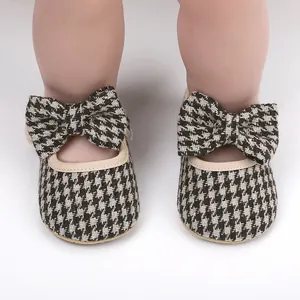 Close-up detail of houndstooth pattern baby girl walking shoes with decorative bow