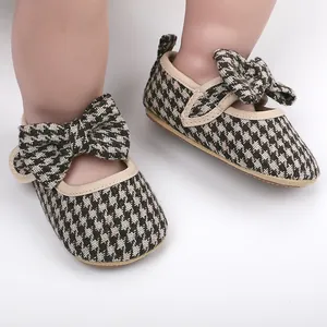 Close-up detail of infant girl houndstooth pattern walker shoes with cute bow design