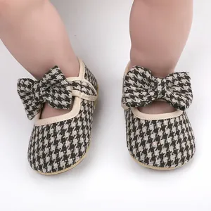Detailed macro view of infant soft walking shoes with classic houndstooth pattern and bow