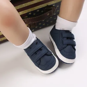 Close-up detail of navy blue baby pre-walker shoes with white soles and dual velcro straps