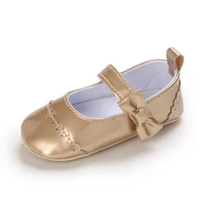 Close-up detail of golden metallic baby Mary Jane princess shoes with a bow decoration