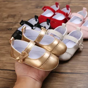 Close-up of metallic gold baby princess shoes with bow detail and multiple colors on wood