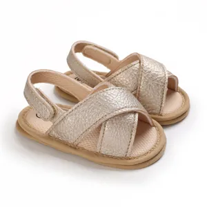 Primer plano de sandalias para bebé color oro champán con suelas blandas y correas.