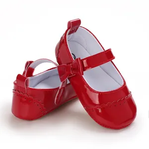 Close-up detail of bright red patent leather baby princess shoes with charming bow