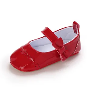 Detailed side view of glossy red baby Mary Jane shoe featuring a bow and scalloped trim