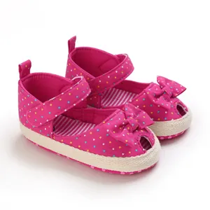 Detailopname van roze babysandalen met stippen, decoratieve strik en zachte zool van touw