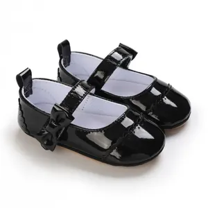 Detail view of glossy black patent leather baby girl shoes with elegant bow accent