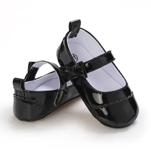 Detail showing glossy black patent leather baby princess shoes with a bow decoration
