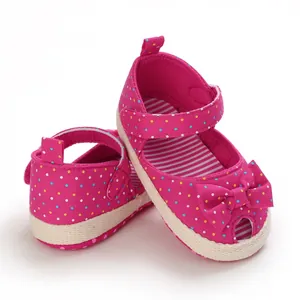 Detail van roze babysandalen met stippen, een schattige strik en zachte zool