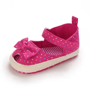 Detailopname van de roze babyschoen met stippen, het strikje en de rand van de textuurzool
