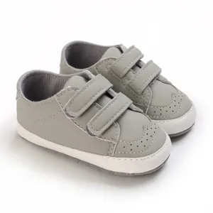 Grey soft sole baby walker shoes with velcro straps and decorative perforation details