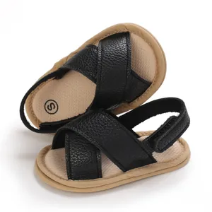 Vista detallada de sandalias de bebé con tiras de cuero sintético negro y suelas beige.