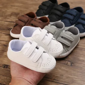 Detailed view of soft-sole white baby walking shoes with Velcro straps and brogue style