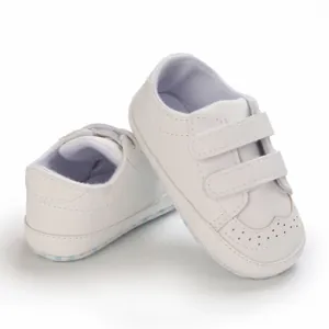 Detailed view of white baby pre-walker shoes with double Velcro straps and brogue detailing