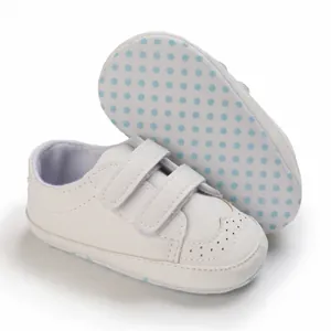 Detail view of white soft sole baby walking shoes with dual velcro straps and polka dots
