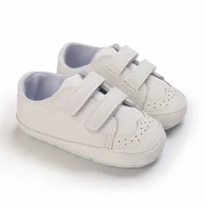Close-up view of white soft sole baby walking shoes featuring double velcro straps