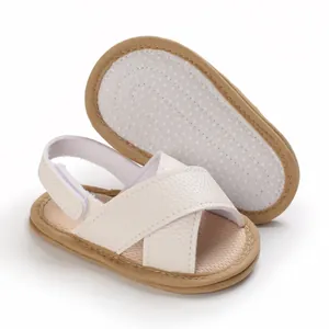 Primer plano de sandalias blancas para bebé con suela blanda y detalles antideslizantes