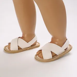 Primer plano de sandalias para bebé blanco crema con suela blanda y correas cruzadas