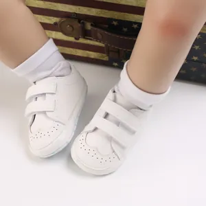 Close-up of white soft-sole baby walker shoes with velcro straps and brogue detailing