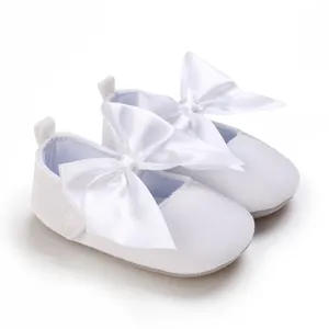 Vue détaillée de chaussures de princesse bébé blanches avec de grands nœuds en satin