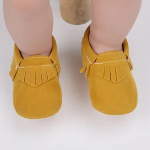 Detailansicht der gelben Wildleder-Babyschuhe mit Fransen und weißen Kontrastnähten
